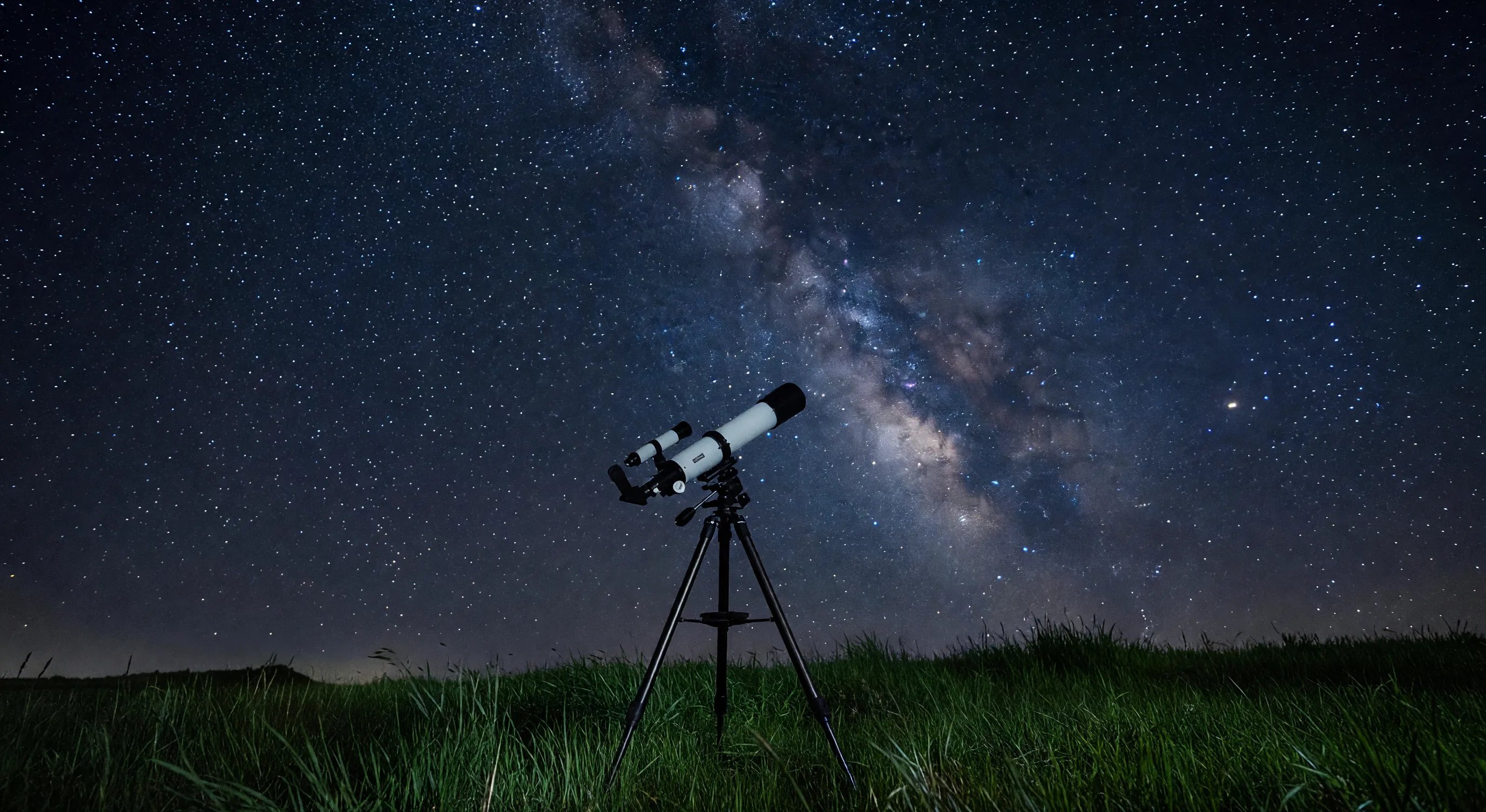 Amateur telescope set up under a starry night sky